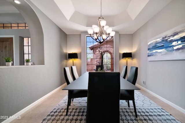 dining room with a chandelier and a raised ceiling