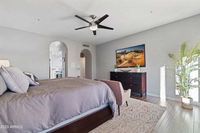 bedroom featuring ceiling fan, ensuite bathroom, and light wood-type flooring