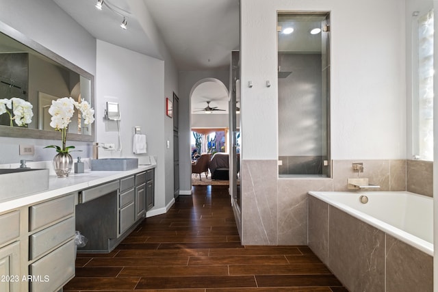 bathroom featuring vanity, tiled tub, a healthy amount of sunlight, and ceiling fan