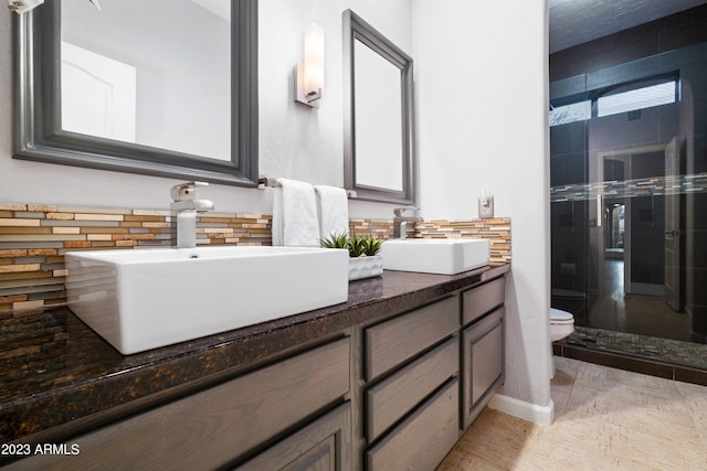 bathroom featuring tasteful backsplash, vanity, toilet, and walk in shower