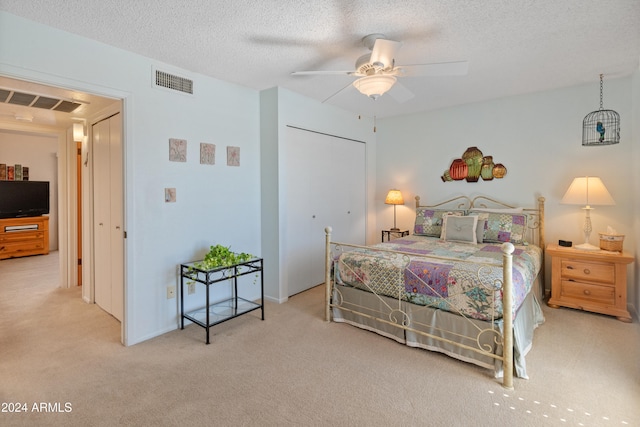 carpeted bedroom with a closet, a textured ceiling, and ceiling fan