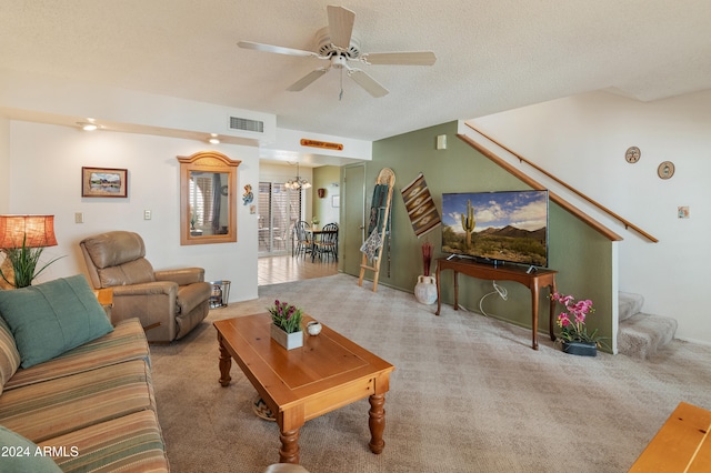 carpeted living room featuring a textured ceiling and ceiling fan with notable chandelier