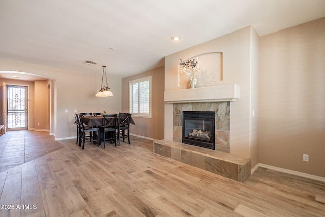 living room with arched walkways, visible vents, plenty of natural light, and wood finished floors