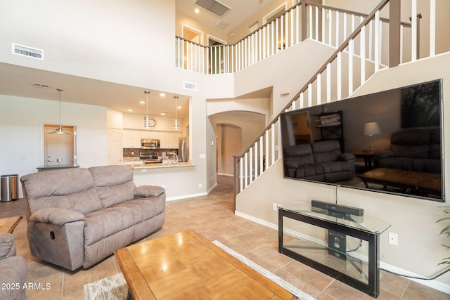 living room featuring visible vents, arched walkways, a high ceiling, and stairway