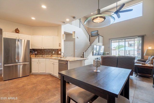kitchen featuring open floor plan, a high ceiling, appliances with stainless steel finishes, and a sink