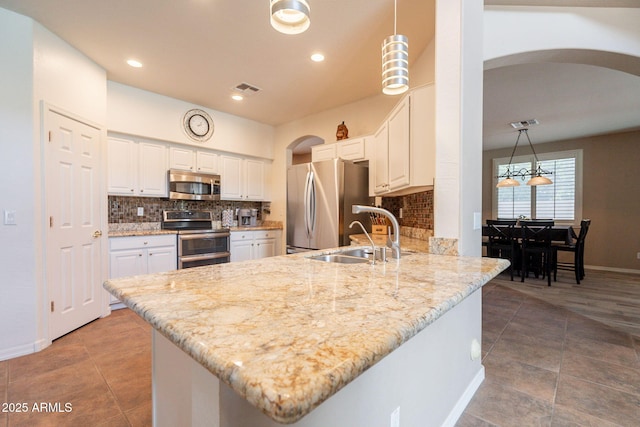 kitchen with visible vents, appliances with stainless steel finishes, arched walkways, a sink, and a peninsula