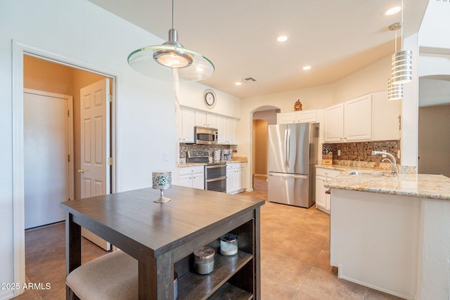 kitchen featuring a sink, a peninsula, arched walkways, backsplash, and stainless steel appliances