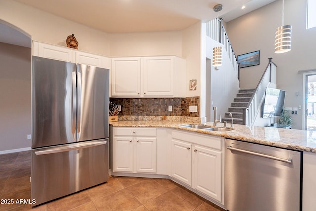 kitchen with decorative backsplash, appliances with stainless steel finishes, a sink, light tile patterned floors, and light stone counters