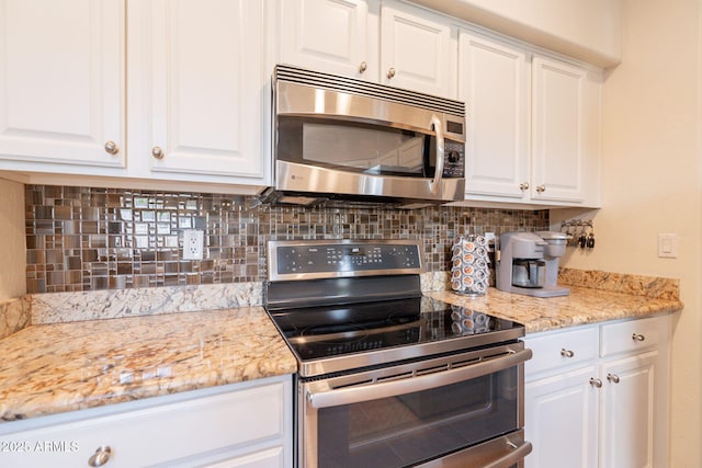 kitchen with backsplash, white cabinets, appliances with stainless steel finishes, and light stone counters