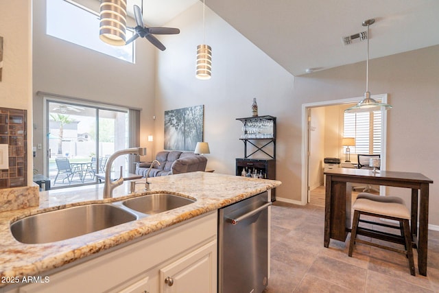 kitchen with light stone counters, a sink, dishwasher, and high vaulted ceiling