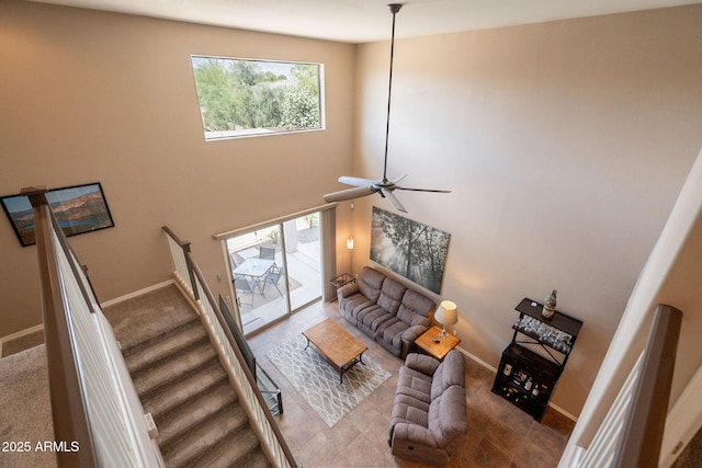 living room featuring stairway, baseboards, and a ceiling fan