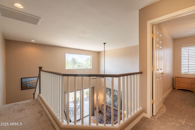 hallway with carpet flooring, a healthy amount of sunlight, and an upstairs landing