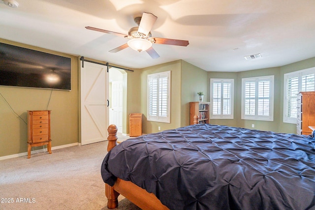 bedroom with visible vents, carpet floors, baseboards, a barn door, and a ceiling fan