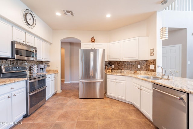 kitchen with visible vents, decorative backsplash, arched walkways, a sink, and appliances with stainless steel finishes