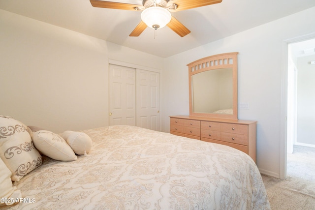 bedroom with ceiling fan, light colored carpet, baseboards, and a closet
