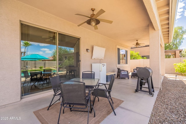 view of patio with outdoor dining area, ceiling fan, and fence
