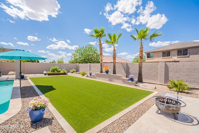 view of yard with a fire pit, a fenced backyard, and a patio area