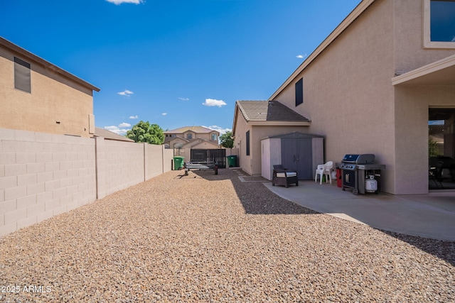 view of yard with a patio, a fenced backyard, an outbuilding, and a storage unit
