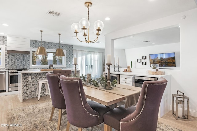 dining space with an inviting chandelier, beverage cooler, and light hardwood / wood-style flooring