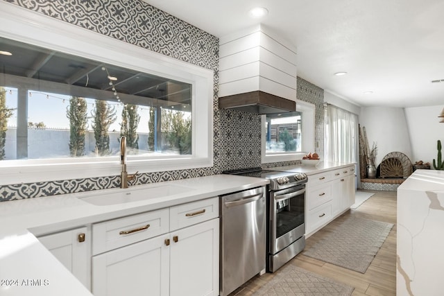 kitchen featuring appliances with stainless steel finishes, white cabinetry, plenty of natural light, and sink