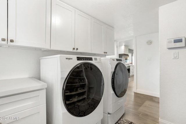 laundry area featuring cabinets, independent washer and dryer, and light hardwood / wood-style flooring