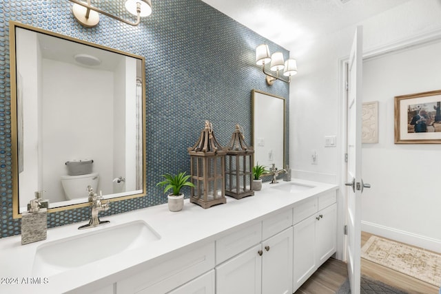 bathroom with hardwood / wood-style flooring, vanity, toilet, and a textured ceiling