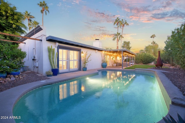 pool at dusk featuring a patio area