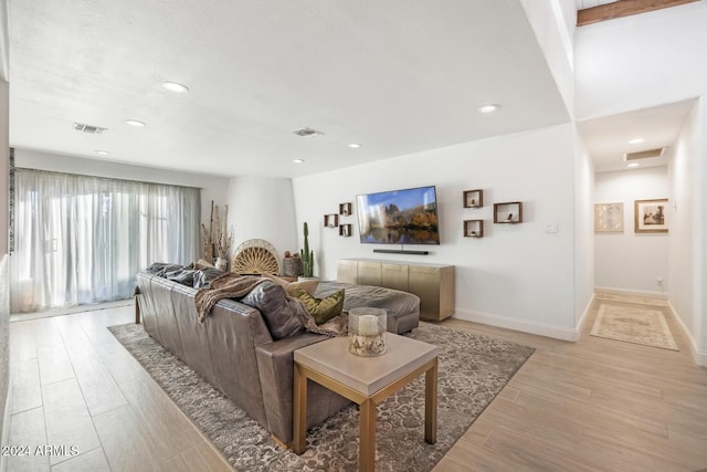 living room with beamed ceiling and light hardwood / wood-style floors