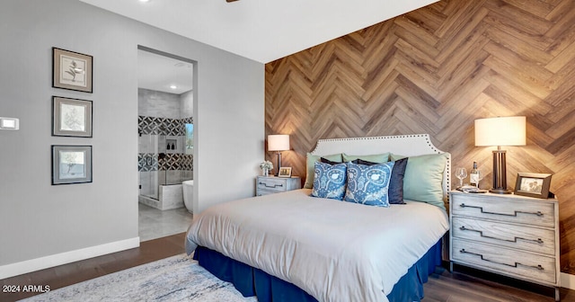 bedroom with ensuite bathroom, wood finished floors, and baseboards