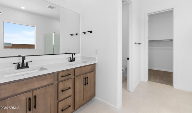 bathroom with a stall shower, a sink, toilet, and double vanity