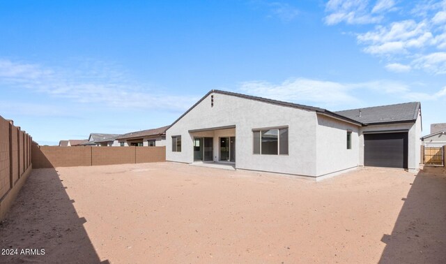 rear view of property with a garage, a fenced backyard, and stucco siding