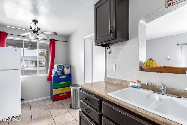 kitchen featuring sink, a textured ceiling, light tile patterned floors, white refrigerator, and ceiling fan