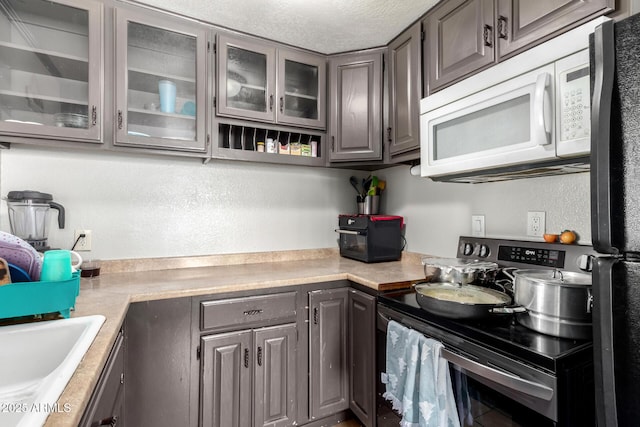 kitchen with sink, fridge, range with electric cooktop, and a textured ceiling