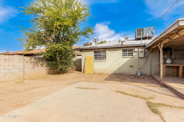 rear view of house with central AC unit and a patio