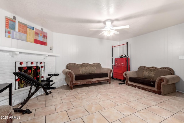 tiled living room featuring a brick fireplace, a textured ceiling, and ceiling fan