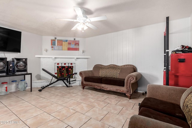 tiled living room featuring ceiling fan, a brick fireplace, and wood walls