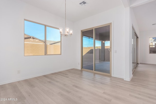 unfurnished dining area with light hardwood / wood-style floors, a healthy amount of sunlight, and an inviting chandelier