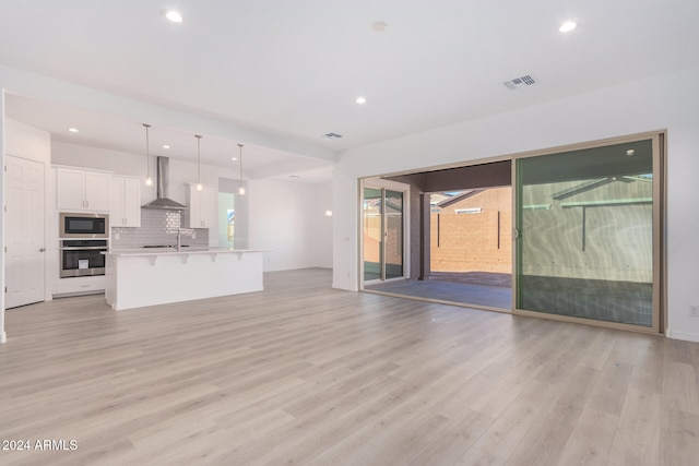 unfurnished living room featuring sink and light hardwood / wood-style flooring