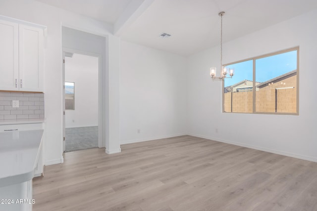 unfurnished dining area with a chandelier and light wood-type flooring