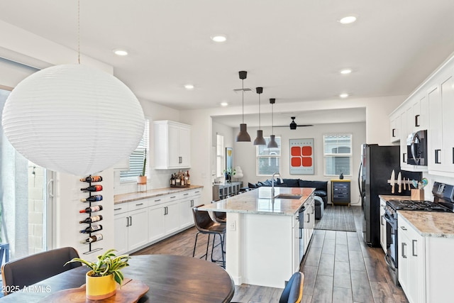 kitchen with a sink, wood finished floors, a kitchen island with sink, and stainless steel appliances