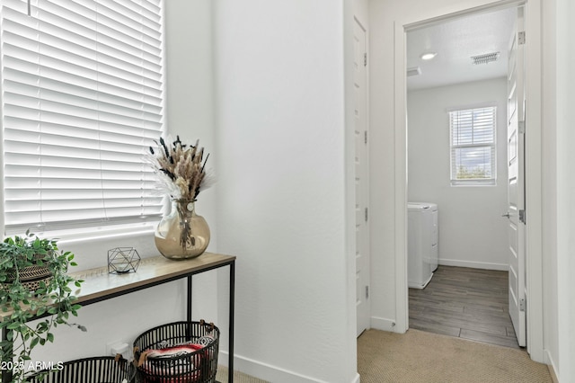 corridor featuring visible vents, washer / dryer, baseboards, and wood finished floors