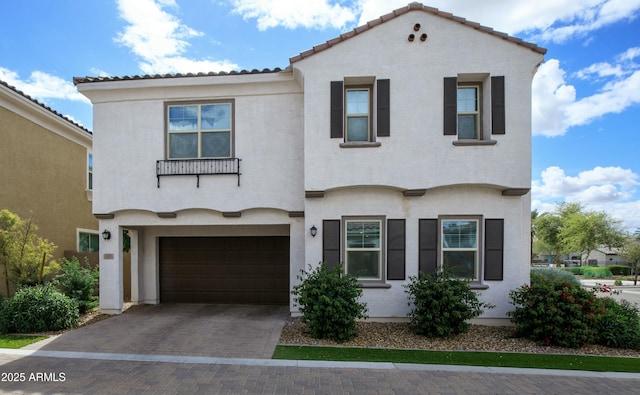 mediterranean / spanish-style house featuring stucco siding, decorative driveway, a garage, and a tile roof