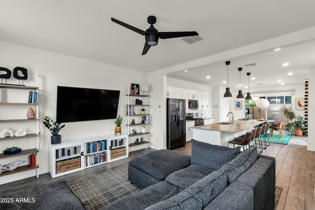 living room featuring ceiling fan, visible vents, wood finished floors, and recessed lighting