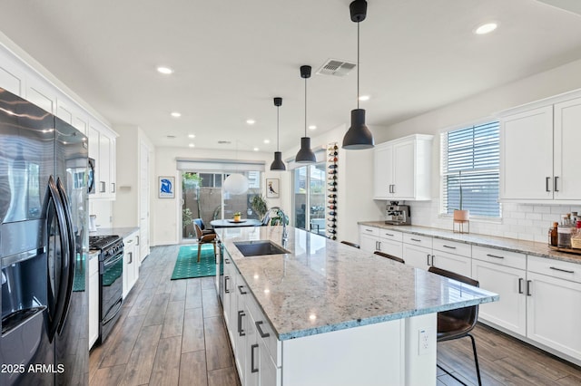 kitchen featuring refrigerator with ice dispenser, black range with gas stovetop, wood finished floors, and a sink