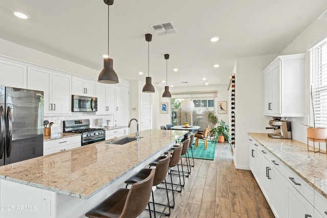 kitchen with a sink, light wood-style flooring, white cabinets, and stainless steel appliances