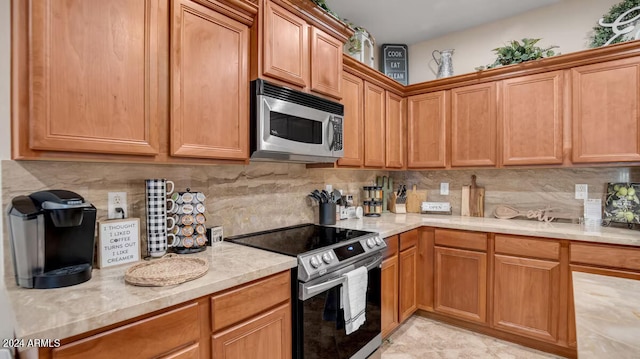 kitchen with brown cabinetry, appliances with stainless steel finishes, decorative backsplash, and light stone counters