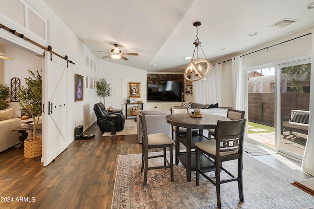 dining area with dark hardwood / wood-style flooring, lofted ceiling, ceiling fan with notable chandelier, and a barn door