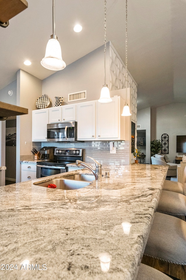 kitchen featuring white cabinetry, appliances with stainless steel finishes, decorative light fixtures, and backsplash