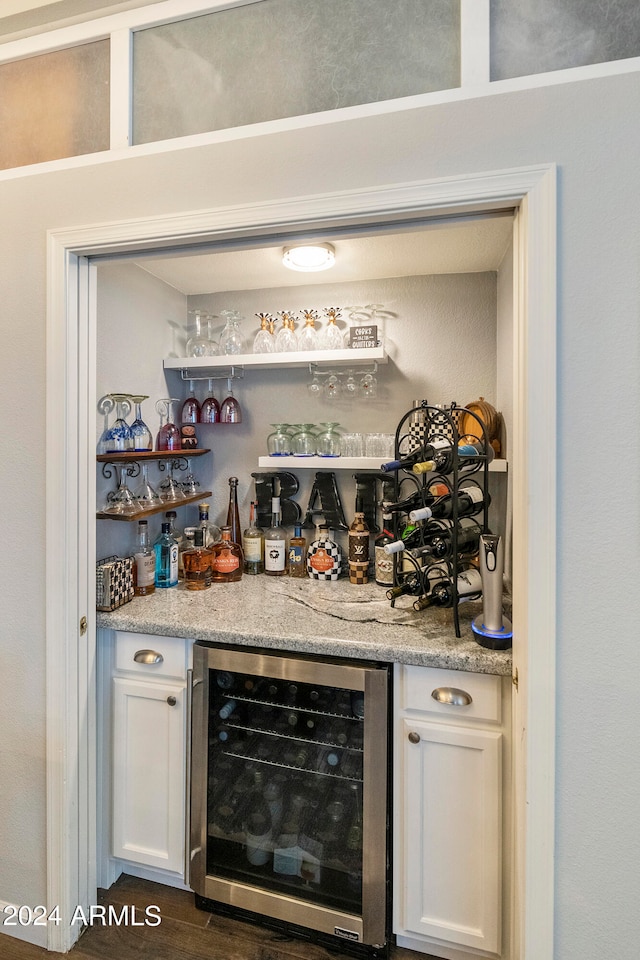 bar featuring light stone counters, dark hardwood / wood-style flooring, wine cooler, and white cabinets