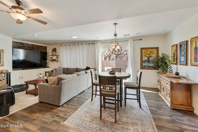 dining room with ceiling fan with notable chandelier and dark hardwood / wood-style floors